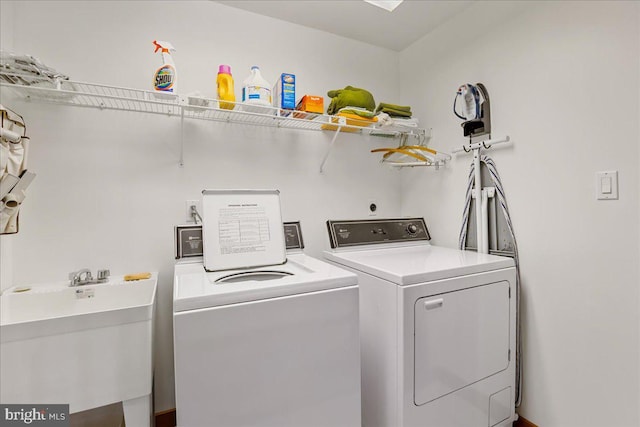 clothes washing area featuring washer and dryer, laundry area, and a sink