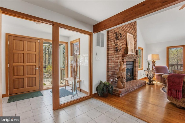 entrance foyer featuring light tile patterned floors, vaulted ceiling with beams, a wealth of natural light, and visible vents