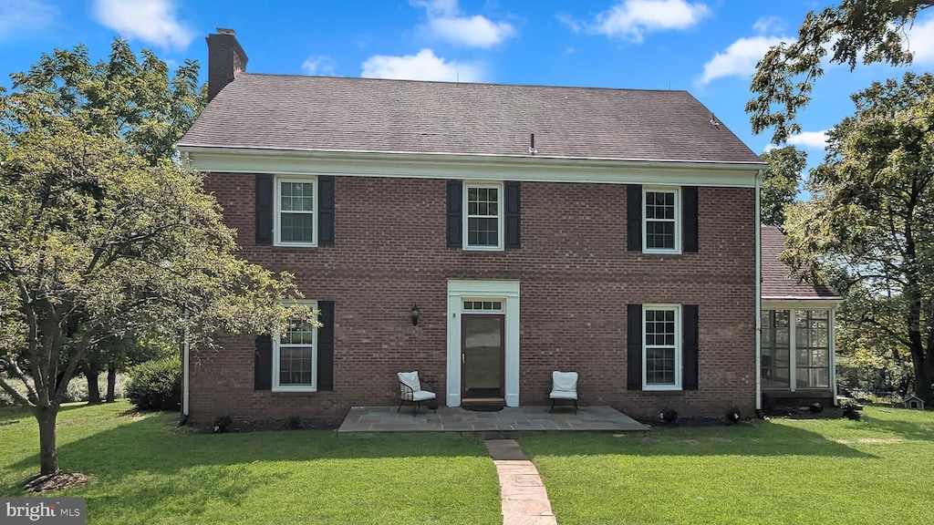 view of front facade featuring a chimney, a patio area, and a front yard