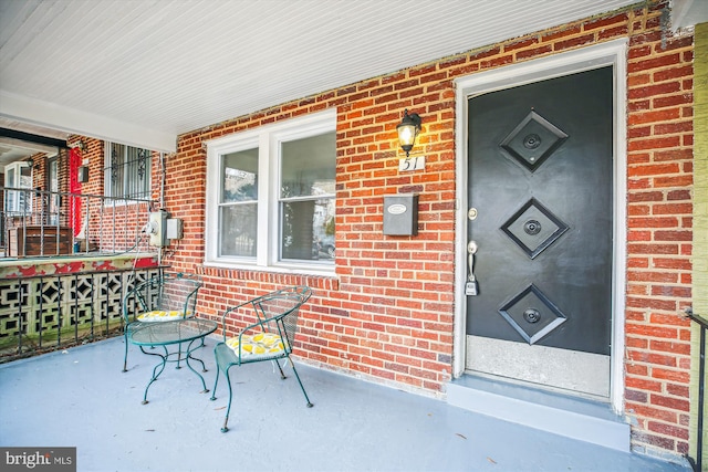 entrance to property with brick siding and a porch