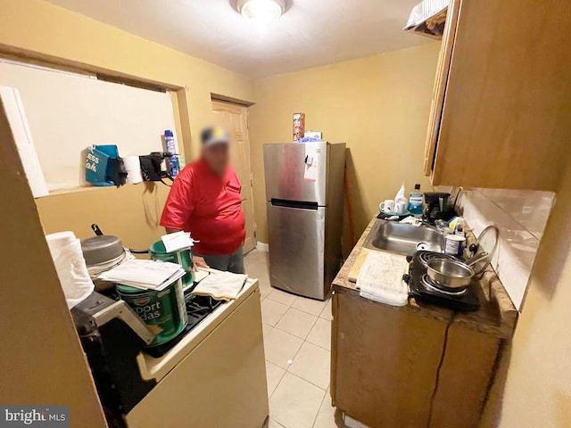 kitchen featuring sink, stainless steel fridge, and light tile patterned flooring