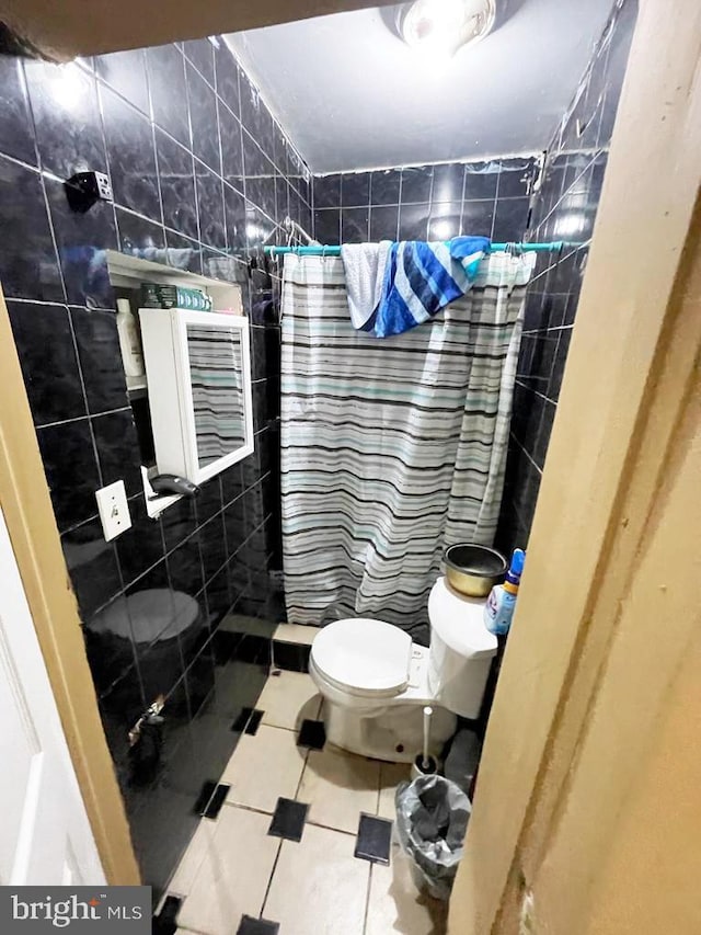 bathroom with toilet, tile walls, tile patterned floors, and a shower with curtain