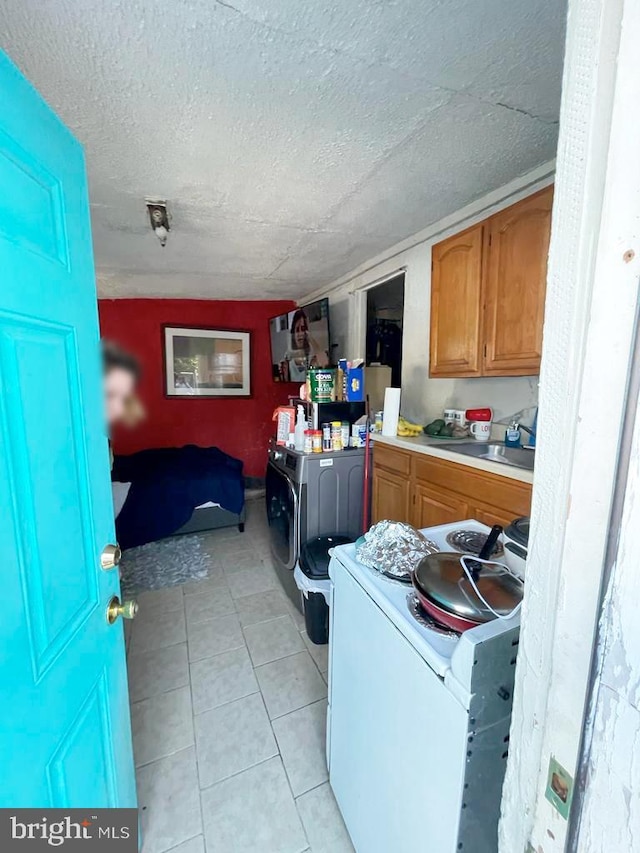 washroom featuring washer / clothes dryer, sink, a textured ceiling, and light tile patterned floors