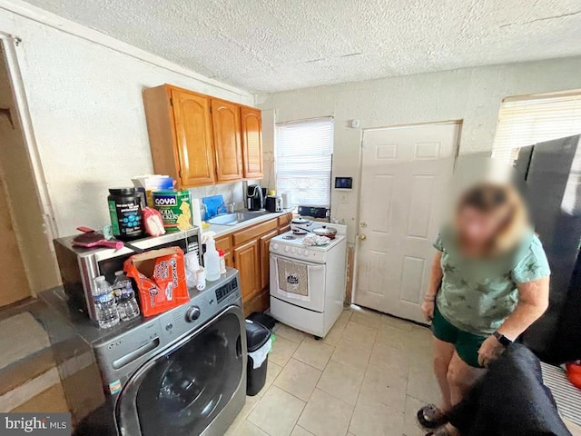 kitchen with washer / dryer, sink, white range oven, light tile patterned floors, and a textured ceiling