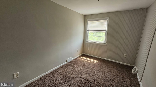 spare room with dark carpet