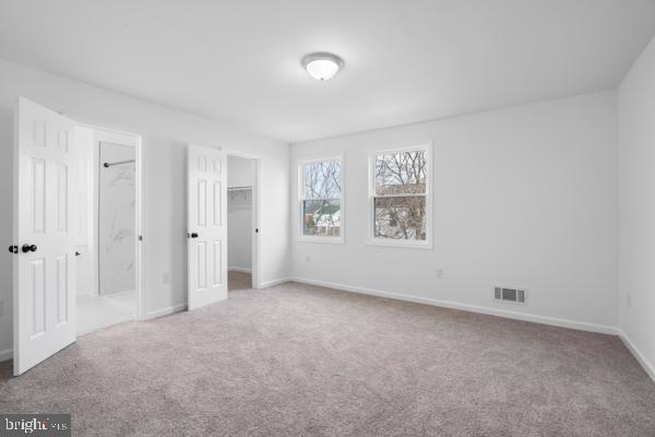 unfurnished bedroom with a walk in closet, carpet floors, and a closet