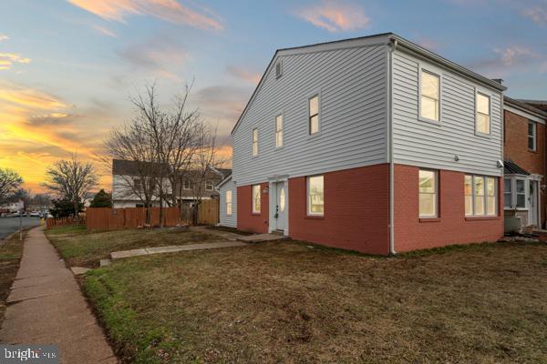 property exterior at dusk featuring a lawn