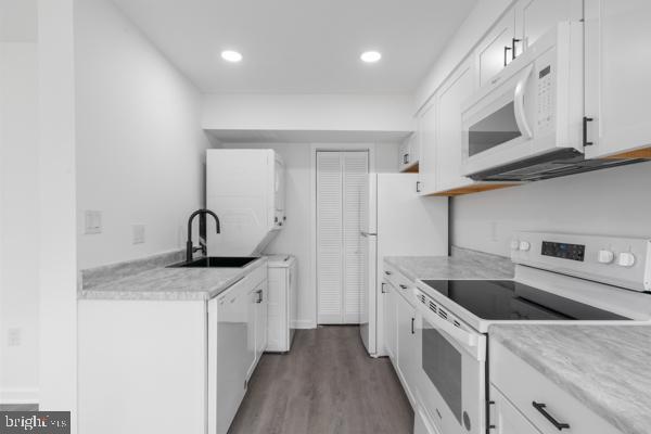 kitchen with sink, white appliances, white cabinets, and hardwood / wood-style flooring