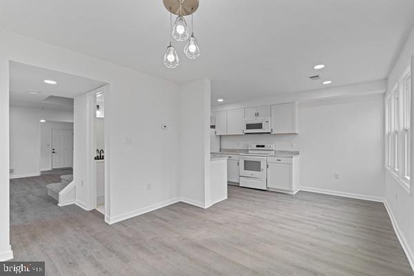 kitchen featuring white cabinetry, hanging light fixtures, white appliances, and light hardwood / wood-style floors