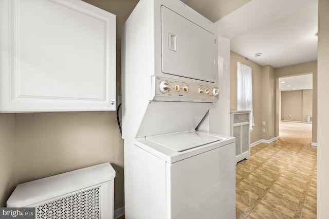 clothes washing area with cabinets and stacked washer and clothes dryer