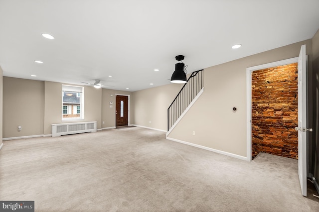 unfurnished living room featuring radiator heating unit and light carpet