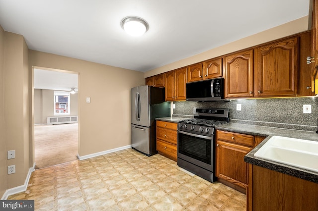 kitchen with radiator, backsplash, stainless steel appliances, and sink