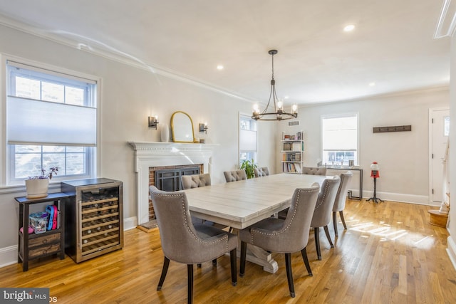 dining room featuring wine cooler, a brick fireplace, crown molding, and plenty of natural light