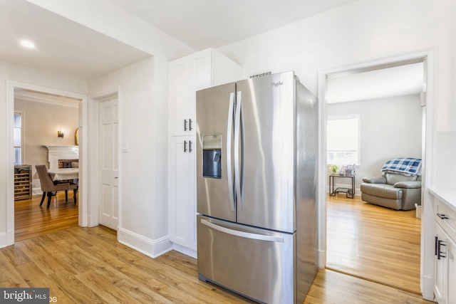 kitchen with white cabinetry, stainless steel fridge, and light hardwood / wood-style floors