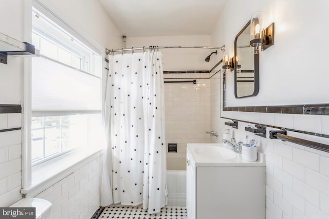 bathroom with shower / bath combo with shower curtain, a healthy amount of sunlight, tile walls, and vanity