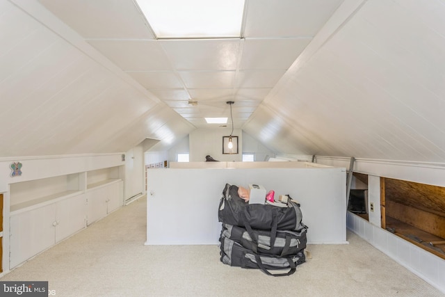 additional living space featuring built in shelves, vaulted ceiling, and light carpet