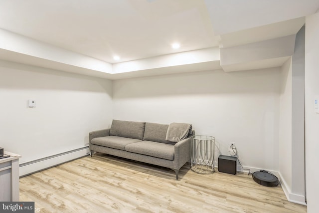 living room with a baseboard heating unit and light hardwood / wood-style flooring