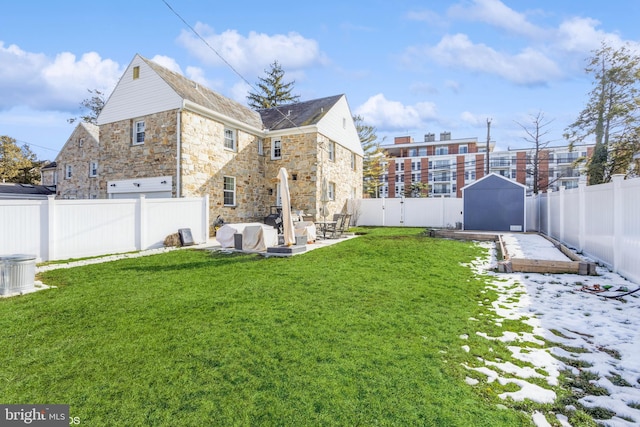 yard layered in snow with a patio and a storage unit