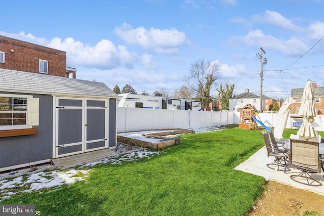 view of yard featuring a patio area, a playground, and a storage unit