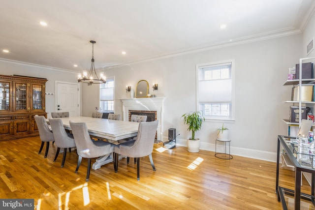 dining space with ornamental molding, light hardwood / wood-style floors, and a chandelier