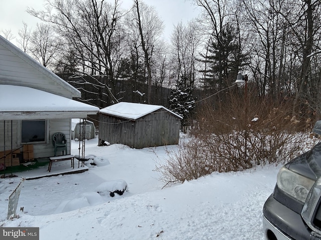 snowy yard featuring a storage shed