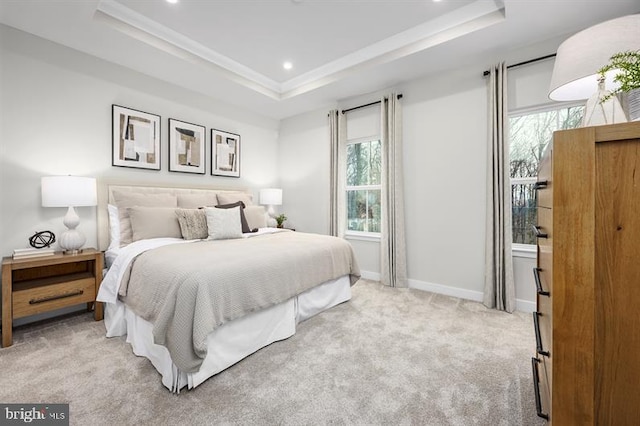 bedroom featuring a raised ceiling, ornamental molding, and light colored carpet