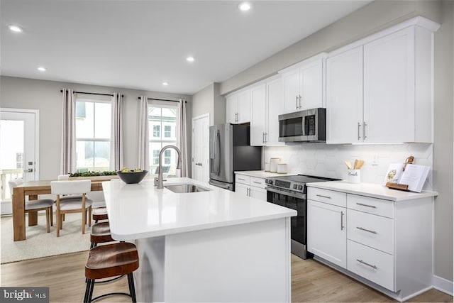 kitchen featuring sink, an island with sink, white cabinets, and appliances with stainless steel finishes