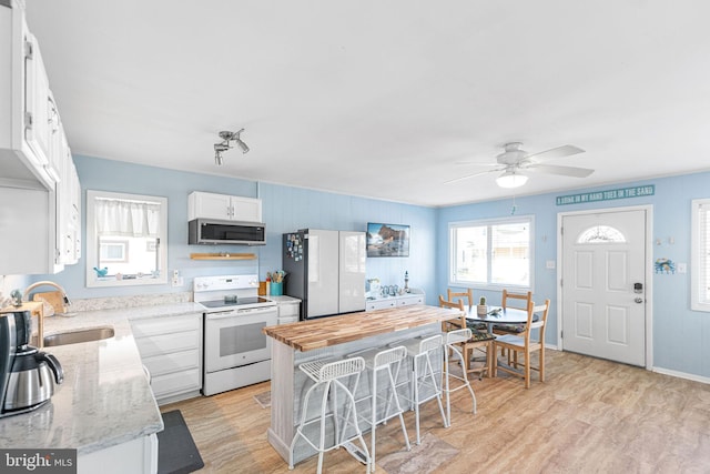 kitchen featuring sink, white appliances, white cabinetry, light stone counters, and light wood-type flooring