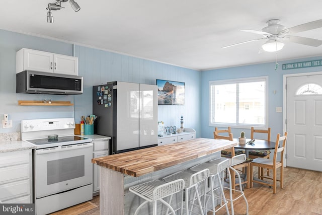 kitchen featuring light stone counters, light wood-type flooring, ceiling fan, white appliances, and white cabinets