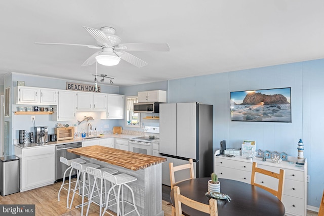 kitchen with a breakfast bar area, light hardwood / wood-style floors, white cabinets, and appliances with stainless steel finishes