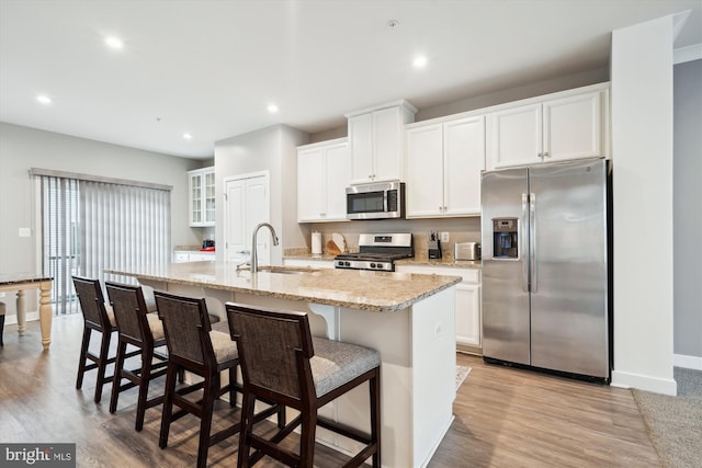 kitchen featuring stainless steel appliances, a kitchen island with sink, sink, and white cabinets