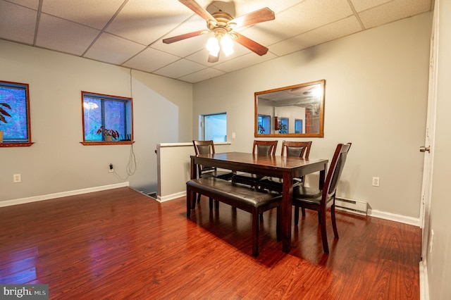 dining area featuring hardwood / wood-style flooring, ceiling fan, baseboard heating, and a drop ceiling