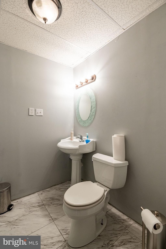 bathroom with a paneled ceiling and toilet