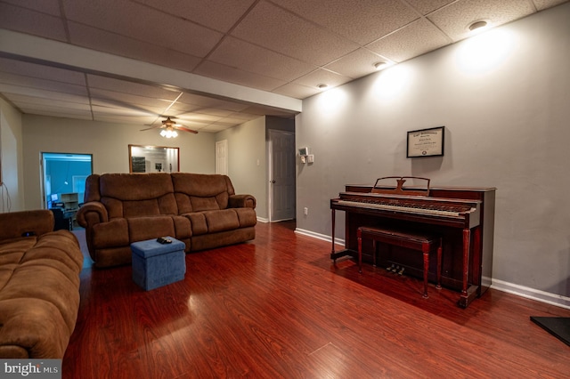 living room with hardwood / wood-style flooring, a paneled ceiling, and ceiling fan