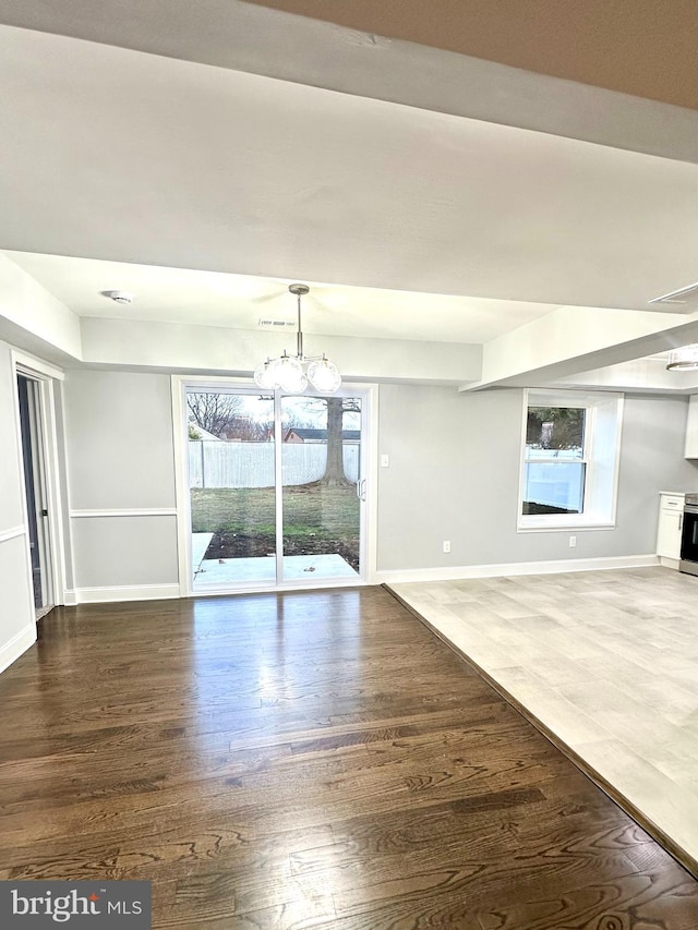 unfurnished dining area with dark wood-type flooring and an inviting chandelier