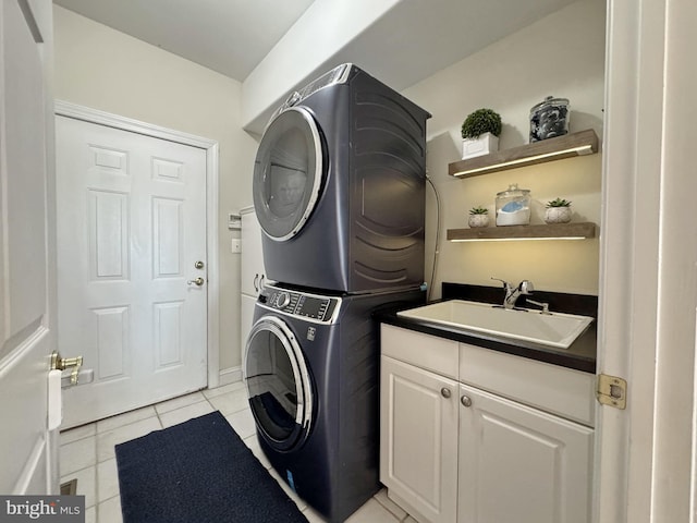 laundry room featuring light tile patterned flooring, cabinets, stacked washing maching and dryer, and sink