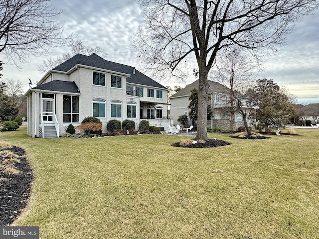 back of property with a sunroom and a lawn