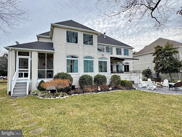 view of front of home with a front lawn, a balcony, and an outdoor fire pit