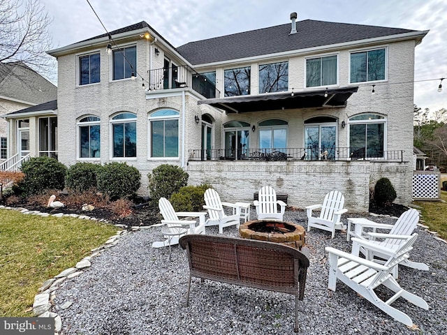 rear view of house featuring a balcony and an outdoor fire pit