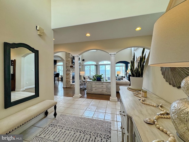 foyer entrance with a towering ceiling, light tile patterned flooring, and ornate columns