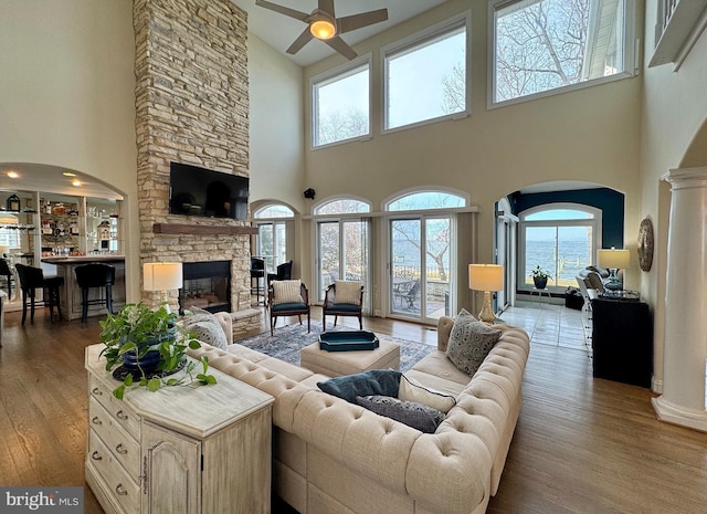 living room featuring decorative columns, wood-type flooring, ceiling fan, and a fireplace