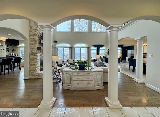 foyer entrance featuring hardwood / wood-style flooring, a high ceiling, and ornate columns