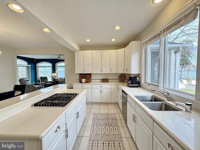 kitchen featuring appliances with stainless steel finishes, white cabinetry, sink, light tile patterned floors, and ceiling fan