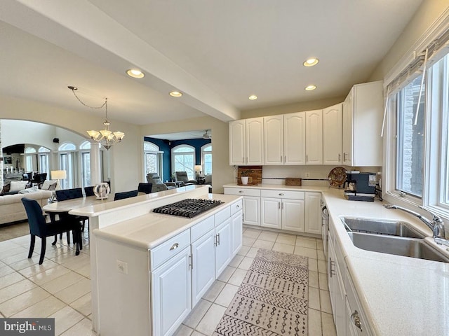 kitchen with pendant lighting, sink, white cabinetry, a kitchen island, and stainless steel gas stovetop