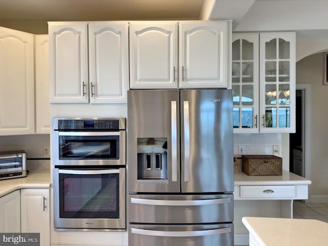 kitchen featuring stainless steel appliances, tasteful backsplash, white cabinets, and tile patterned floors