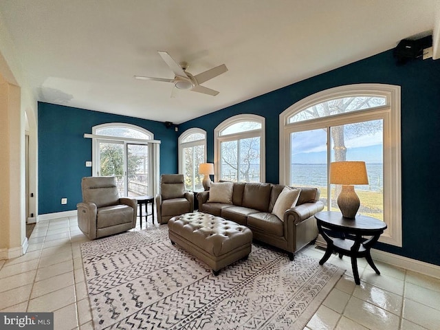 living room featuring a water view, ceiling fan, and light tile patterned floors