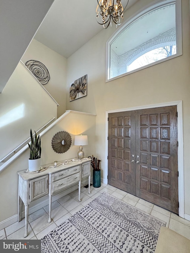 tiled entrance foyer featuring a towering ceiling and a notable chandelier