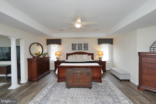 bedroom featuring hardwood / wood-style floors, a raised ceiling, ceiling fan, and ornate columns