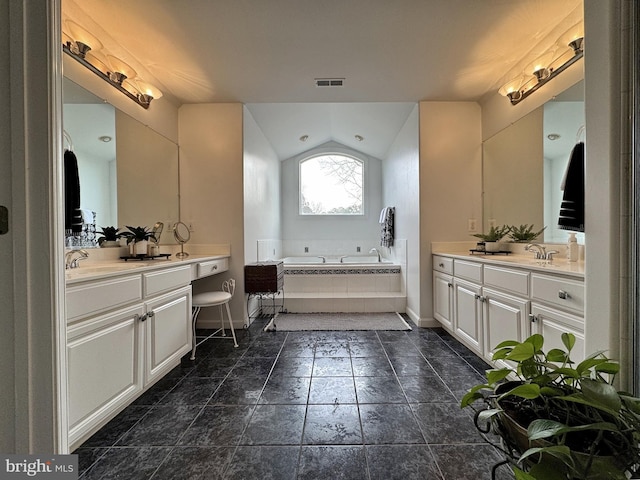 bathroom featuring lofted ceiling, vanity, and tiled tub