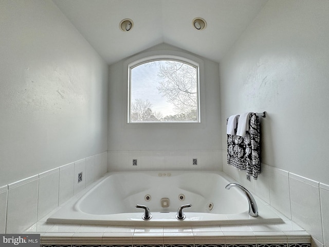 bathroom featuring a relaxing tiled tub and lofted ceiling